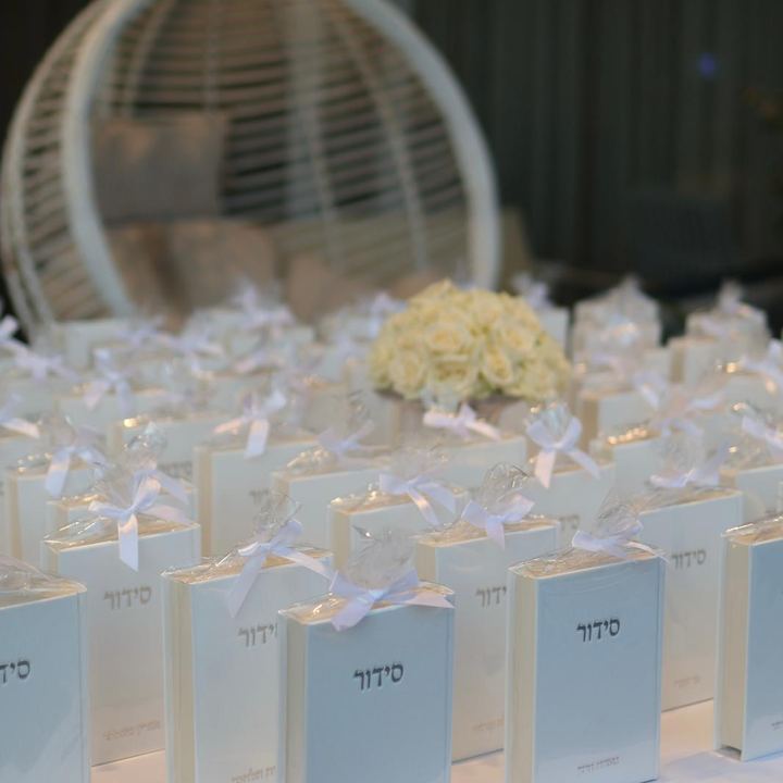 סידורים ומתנות לבנות על שולחן עם כורסת ביצה